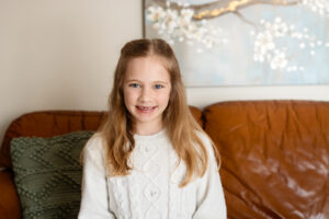 Girl sitting in a living room wearing an off-white sweater