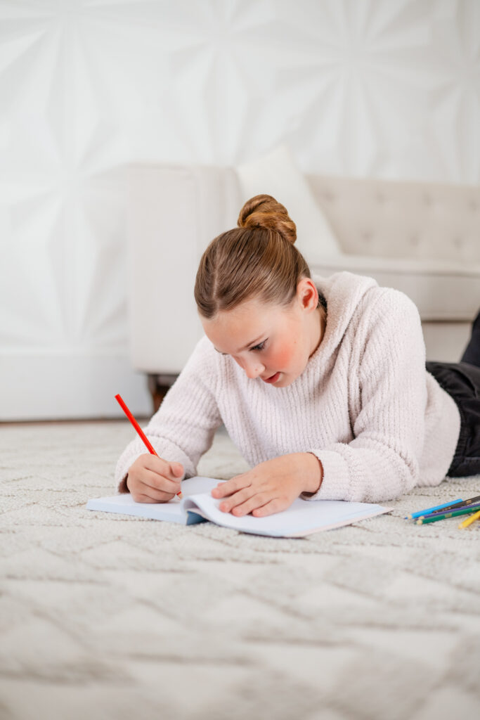 girl laying on the floor, drawing in a journal