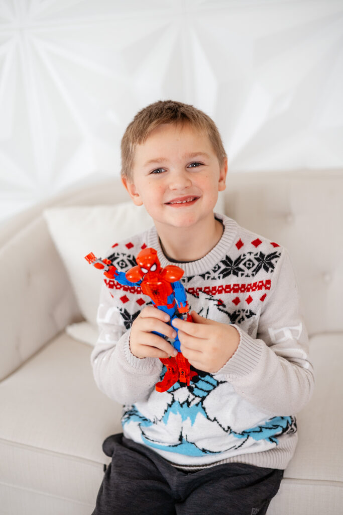 Boy smiling and holding a spiderman toy
