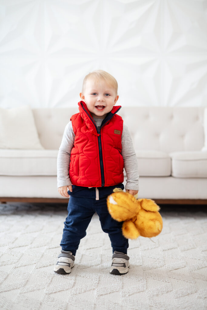 Toddler boy holding a yellow duck and smiling